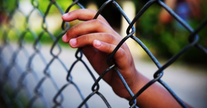 childs hand in fence 